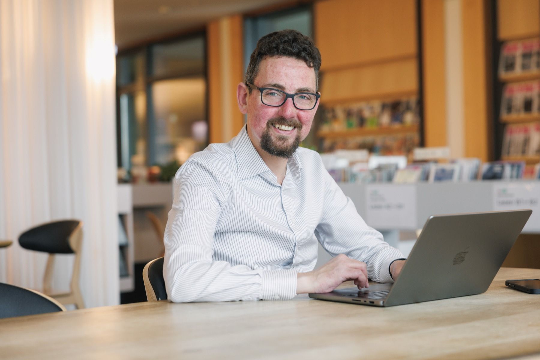 René Goedhart, docent Nederlands, werkt achter zijn laptop in een studeerkamer met boekenkasten